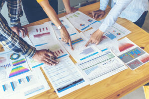 Business team surrounding a table covered in graphs