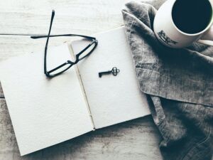 Image of glasses on a notebook with a key and a mug, all on top of a table
